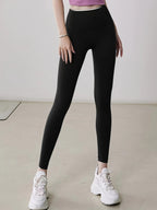 Person wearing black leggings and white sneakers on a plain background