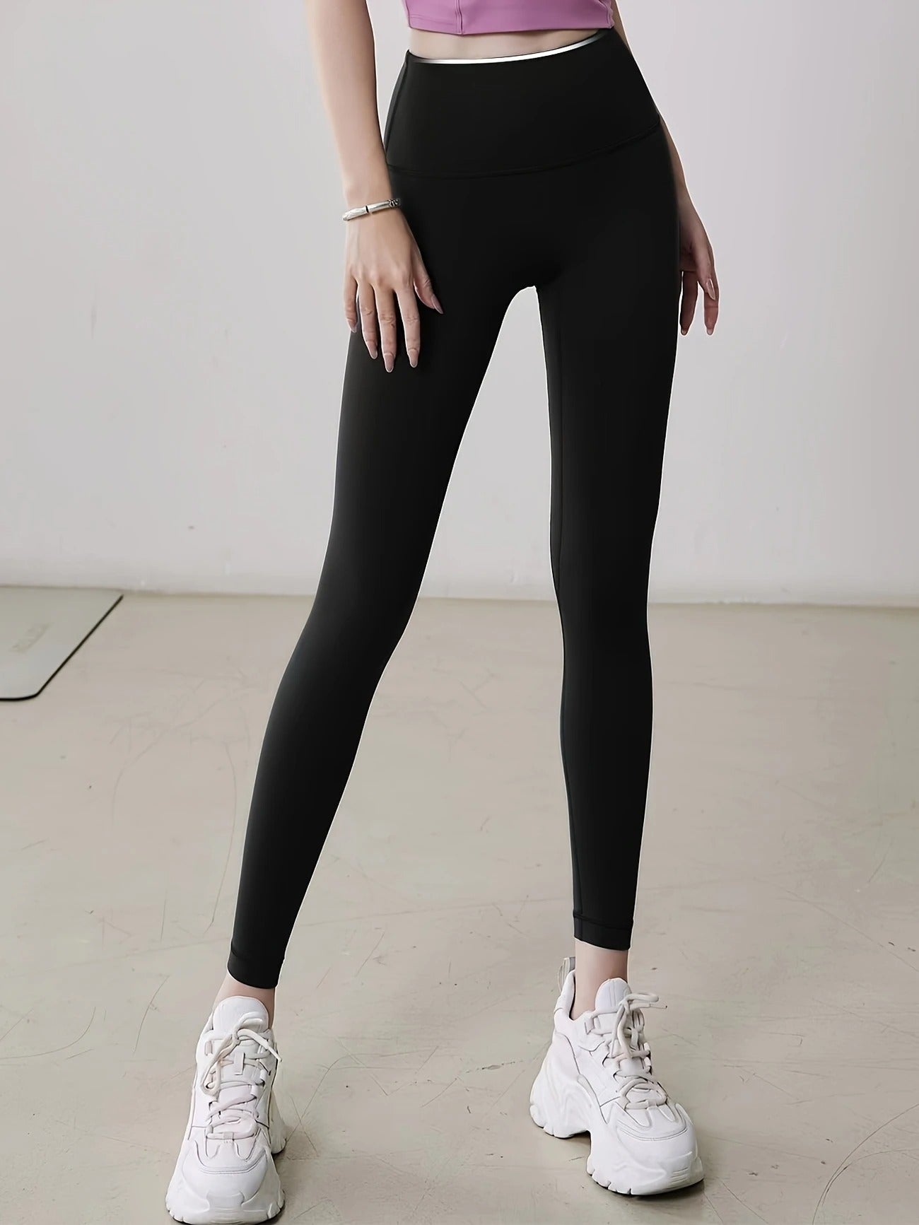 Person wearing black leggings and white sneakers on a plain background