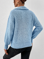 Person wearing a blue knitted sweater and black pants against a white background