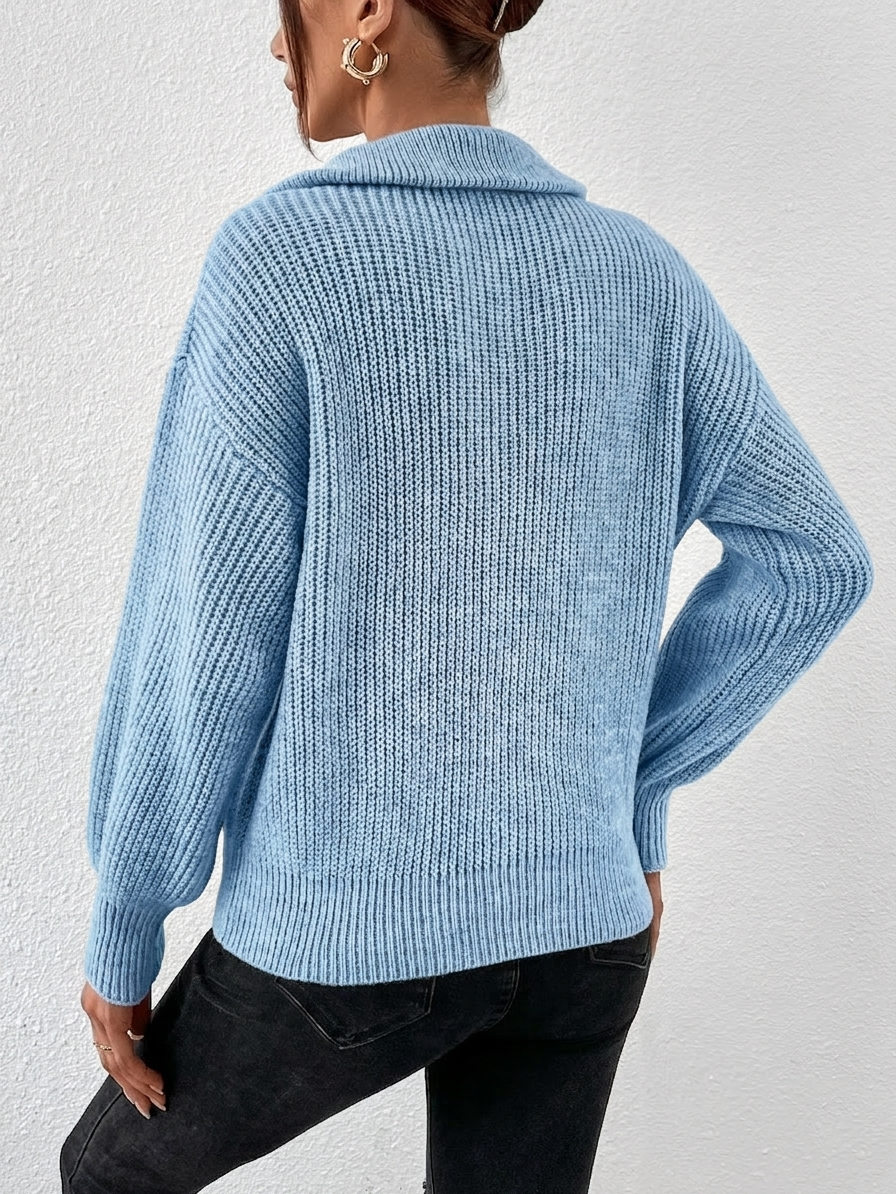 Person wearing a blue knitted sweater and black pants against a white background