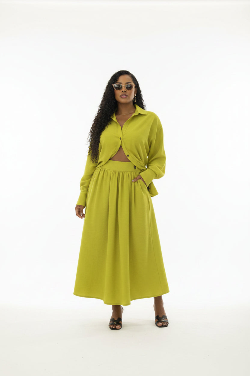 Woman in a bright yellow outfit standing in a whitebackground.