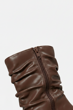 Brown leather boot with a zipper on a light gray background