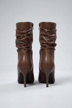 Pair of brown high-heeled boots on a light gray background
