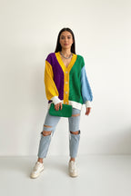 Person wearing a colorful cardigan with a green handbag on a white background