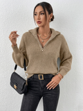 Person wearing a beige knitted sweater and black pants against a white background