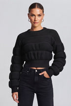 woman wearing a black, textured knit sweater.