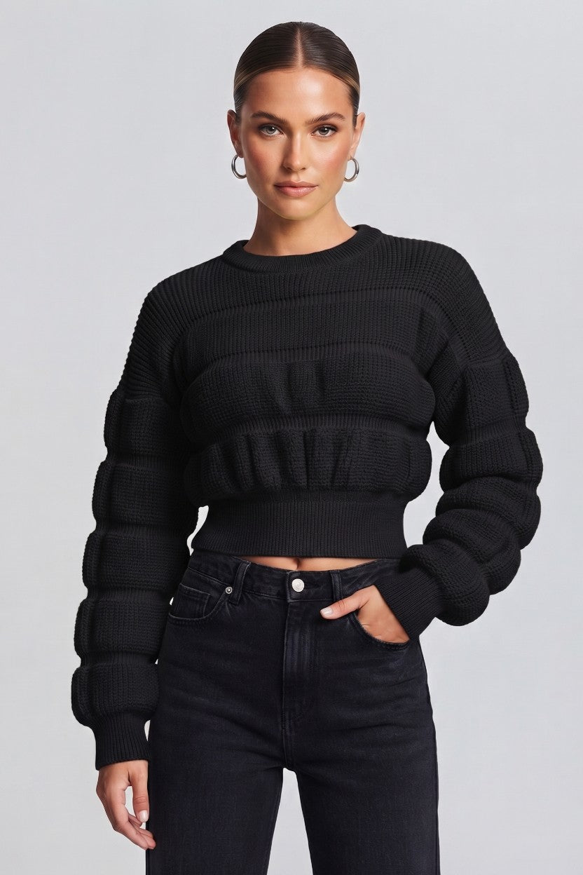 woman wearing a black, textured knit sweater.
