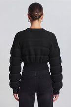 woman wearing a black, textured knit sweater.