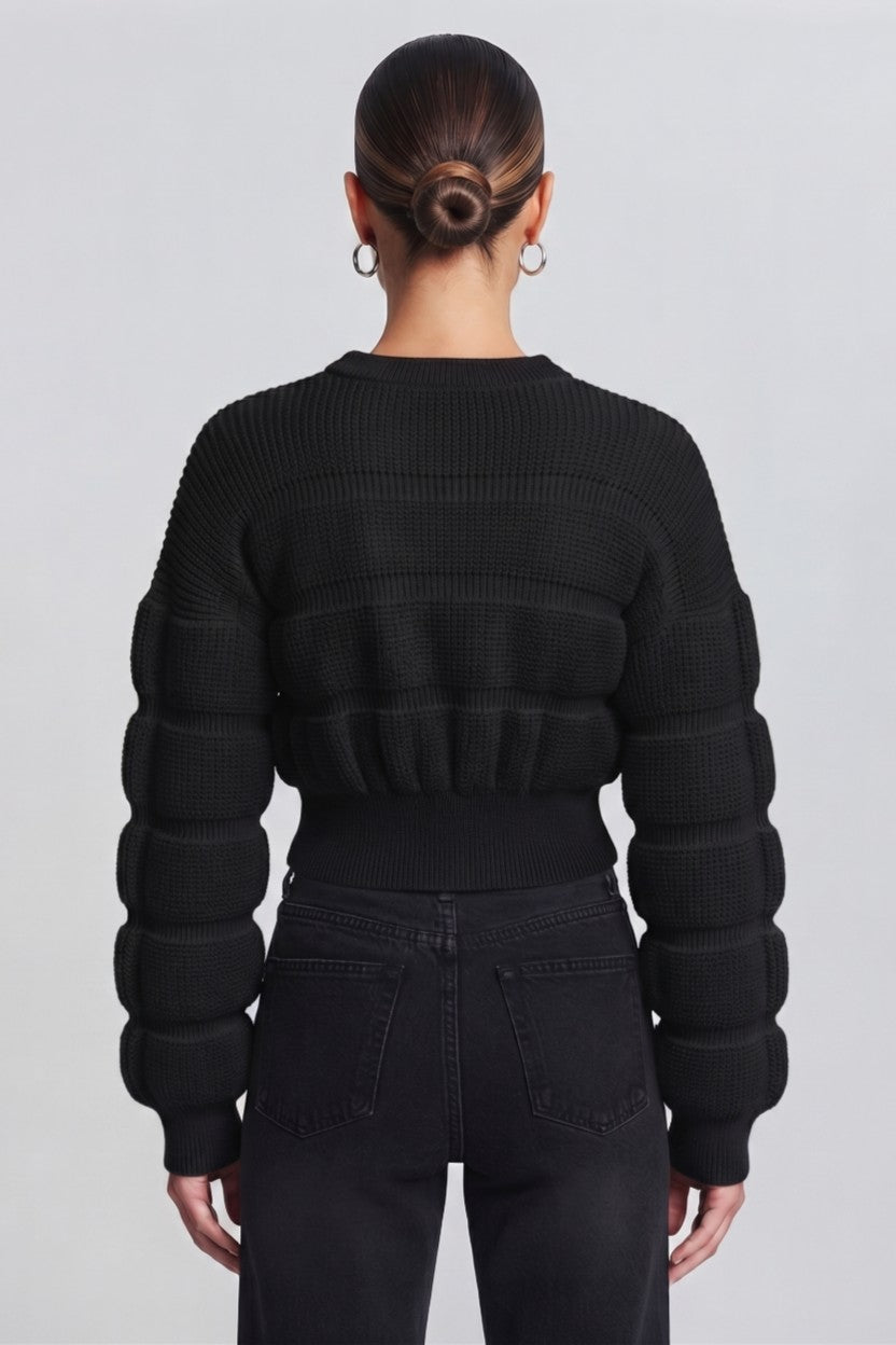woman wearing a black, textured knit sweater.