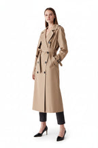 Woman wearing a beige trench coat on a plain background