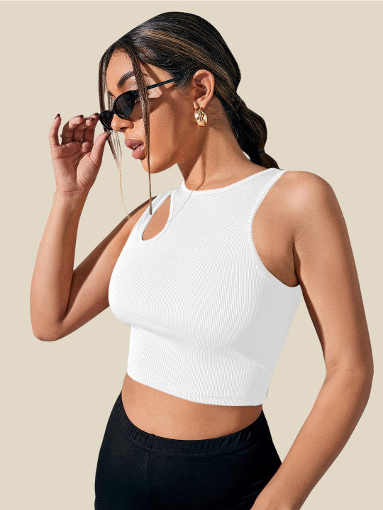 Woman wearing a white sleeveless top and black pants against a beige background