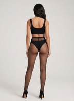 Woman wearing black fishnet stockings and a black top on a white background