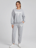 Woman wearing a gray 'blessed' sweatshirt and pants on a white background