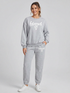 Woman wearing a gray 'blessed' sweatshirt and pants on a white background