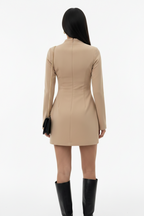 Person wearing a beige dress with long sleeves on a white background