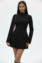 Woman wearing a black dress with long sleeves on a white background