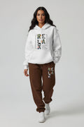 Woman wearing a white hoodie and brown sweatpants with 'RELAX' text.