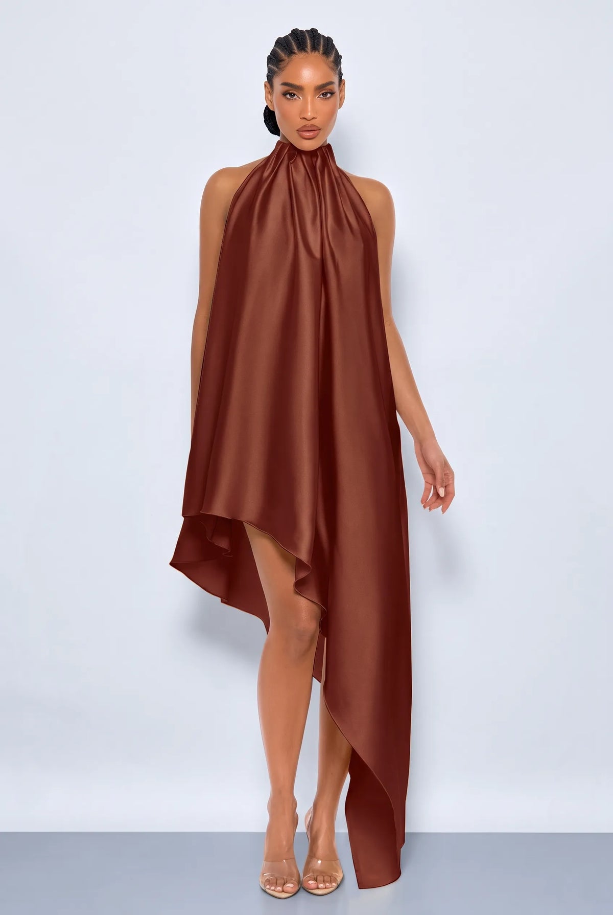 A woman modeling a brown satin halter-neck high-low dress with an open back, shown from a side-back angle against a light gray studio background.
