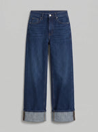 high-waisted dark blue wash wide-leg jeans featuring prominent wide turned-up cuffed hems. 