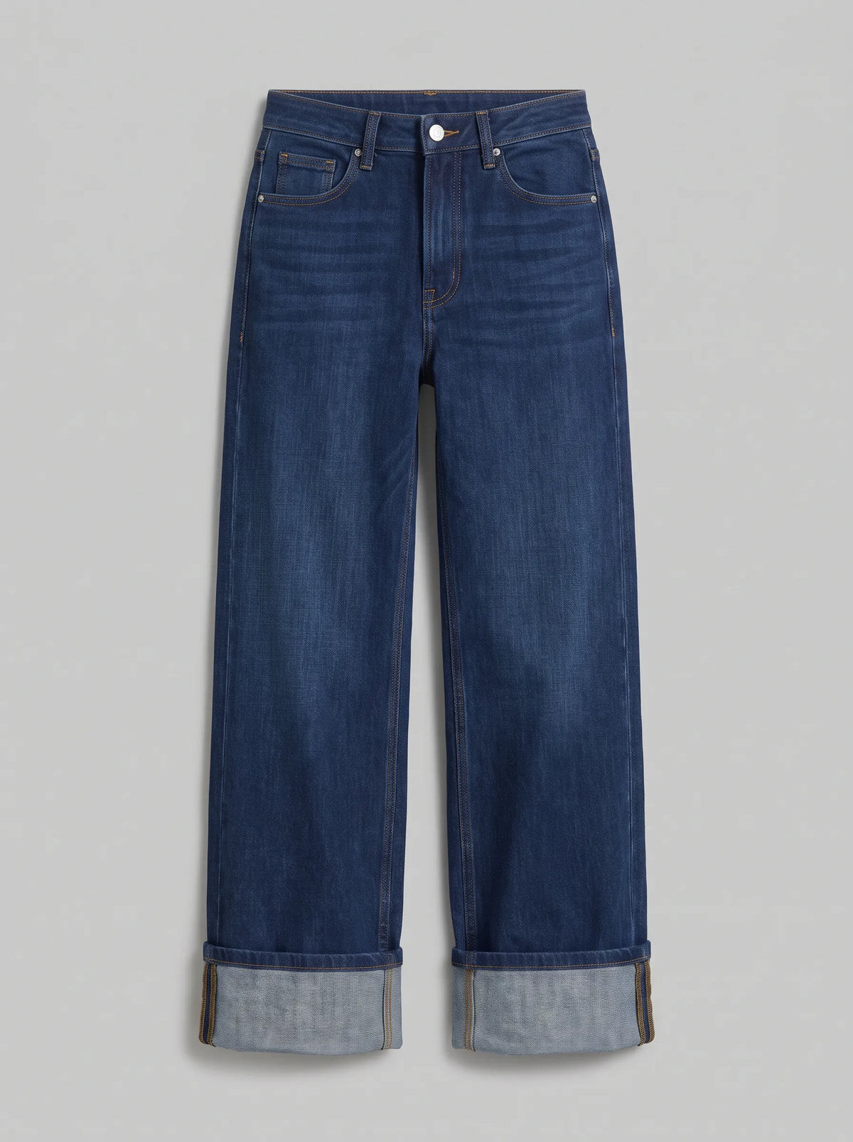 high-waisted dark blue wash wide-leg jeans featuring prominent wide turned-up cuffed hems. 