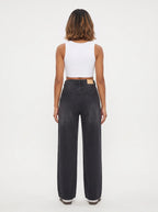 This pair of high-waisted, wide-leg jeans is crafted from a dark washed-black or washed-charcoal denim with subtle whiskering across the lap and gentle vertical fading down the legs.
