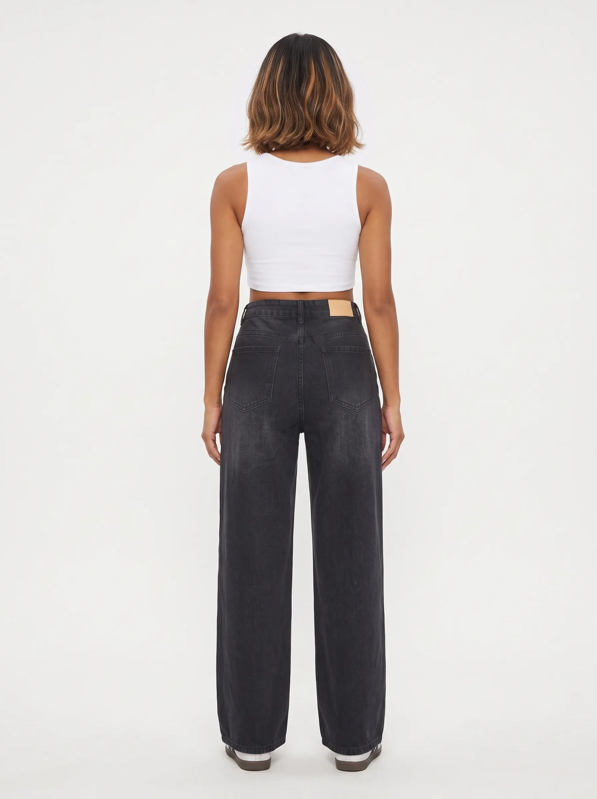 This pair of high-waisted, wide-leg jeans is crafted from a dark washed-black or washed-charcoal denim with subtle whiskering across the lap and gentle vertical fading down the legs.