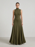 Woman wearing a long green dress against a plain background