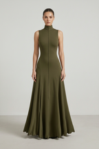 Woman wearing a long green dress against a plain background