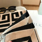 Close-up of a black and beige striped bag with sunglasses on a surface.