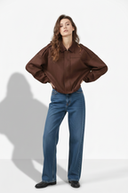 Woman wearing a brown blouse and black pants on a white background