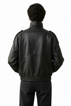 Person wearing a black leather jacket against a plain background