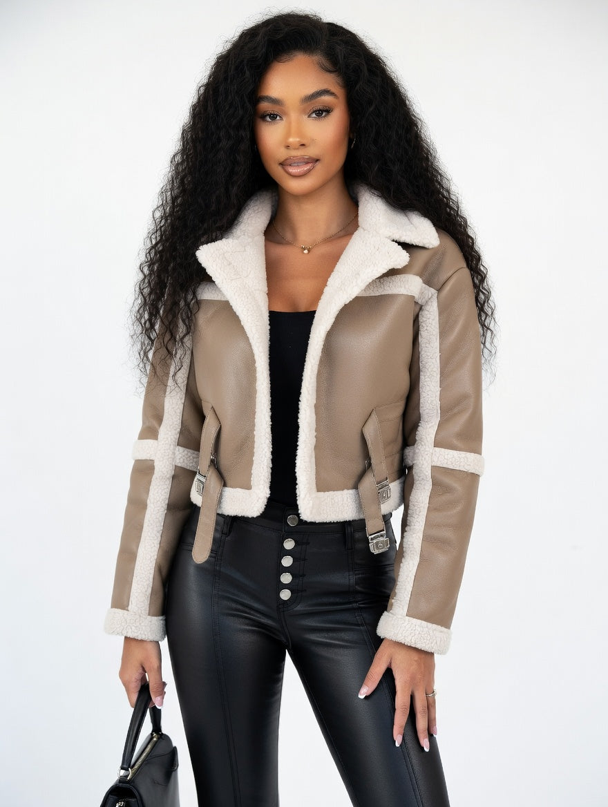 Woman wearing a beige shearling jacket with white trim on a white background