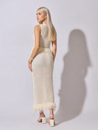 Woman wearing a white crochet dress against a plain background