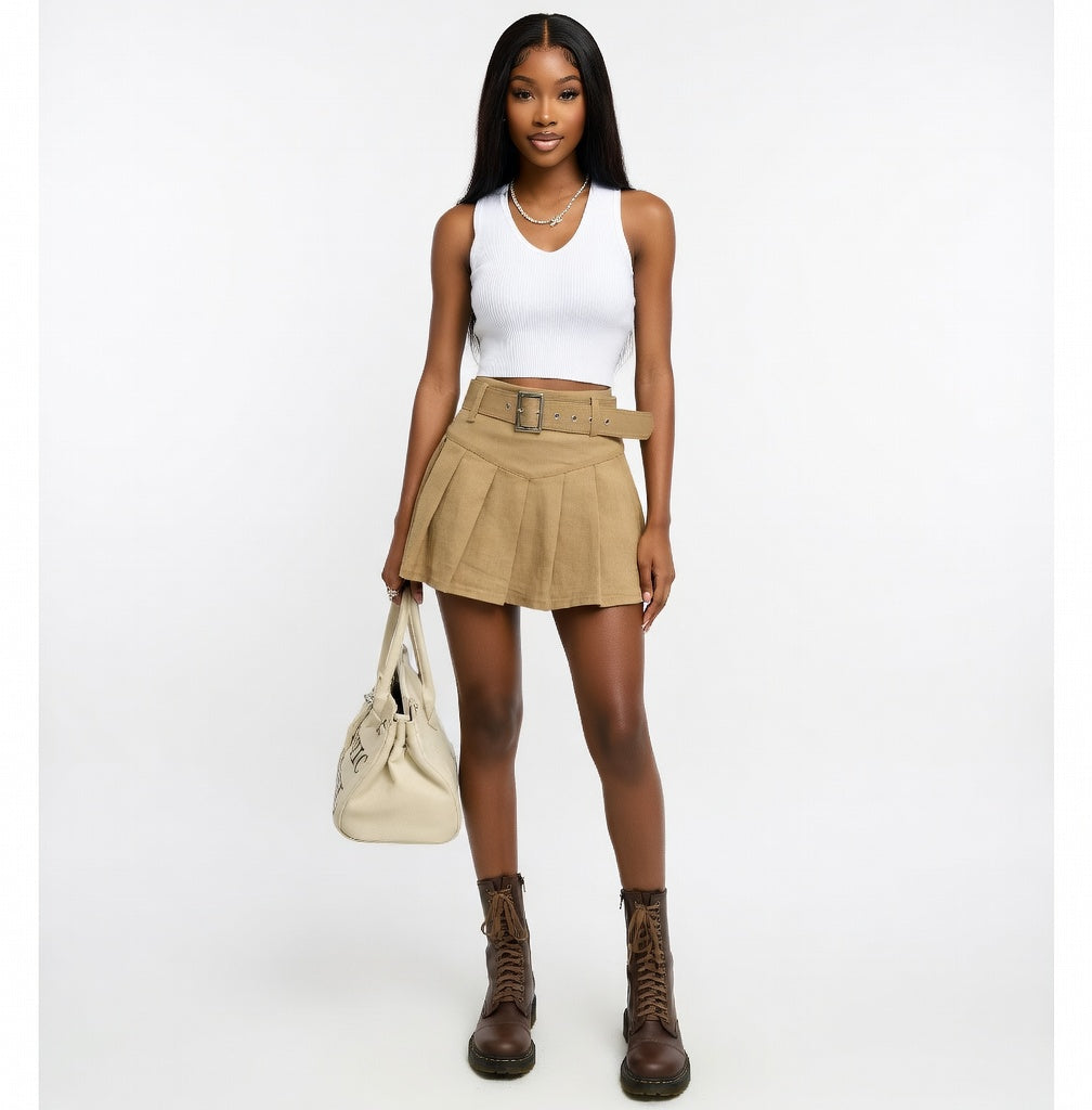 Woman wearing a white tank top, beige skirt, and brown boots on a white background