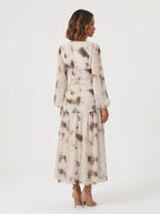 long midi dress crafted from a sheer, flowing fabric featuring an abstract, watercolor-inspired floral print in muted tones of cream, muted purple, sage, and warm amber. 