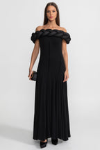 Woman wearing a black off-shoulder dress with braided detailing on a white background