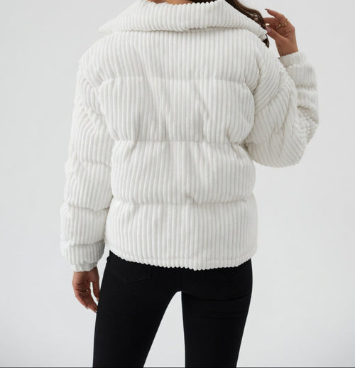 Woman wearing a white ribbed knit puffer jacket on a light gray background