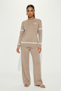 Woman wearing a beige long-sleeve top and pants set on a white background