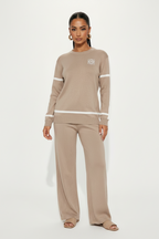 Woman wearing a beige long-sleeve top and pants set on a white background