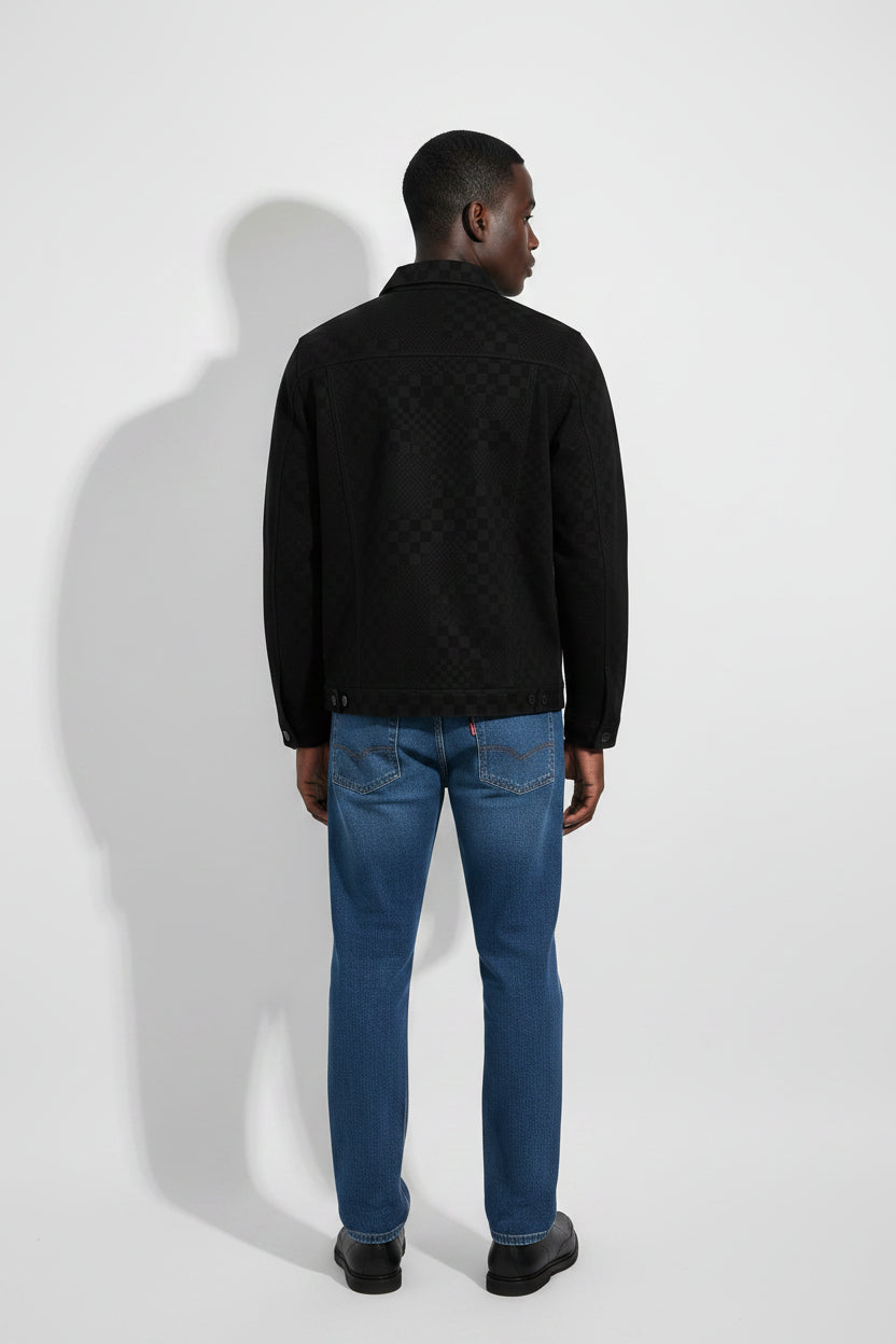 Person wearing a black jacket and blue jeans against a white background