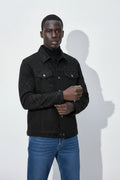 Man wearing a black quilted jacket and blue jeans against a white background