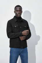 Man wearing a black quilted jacket and blue jeans against a white background
