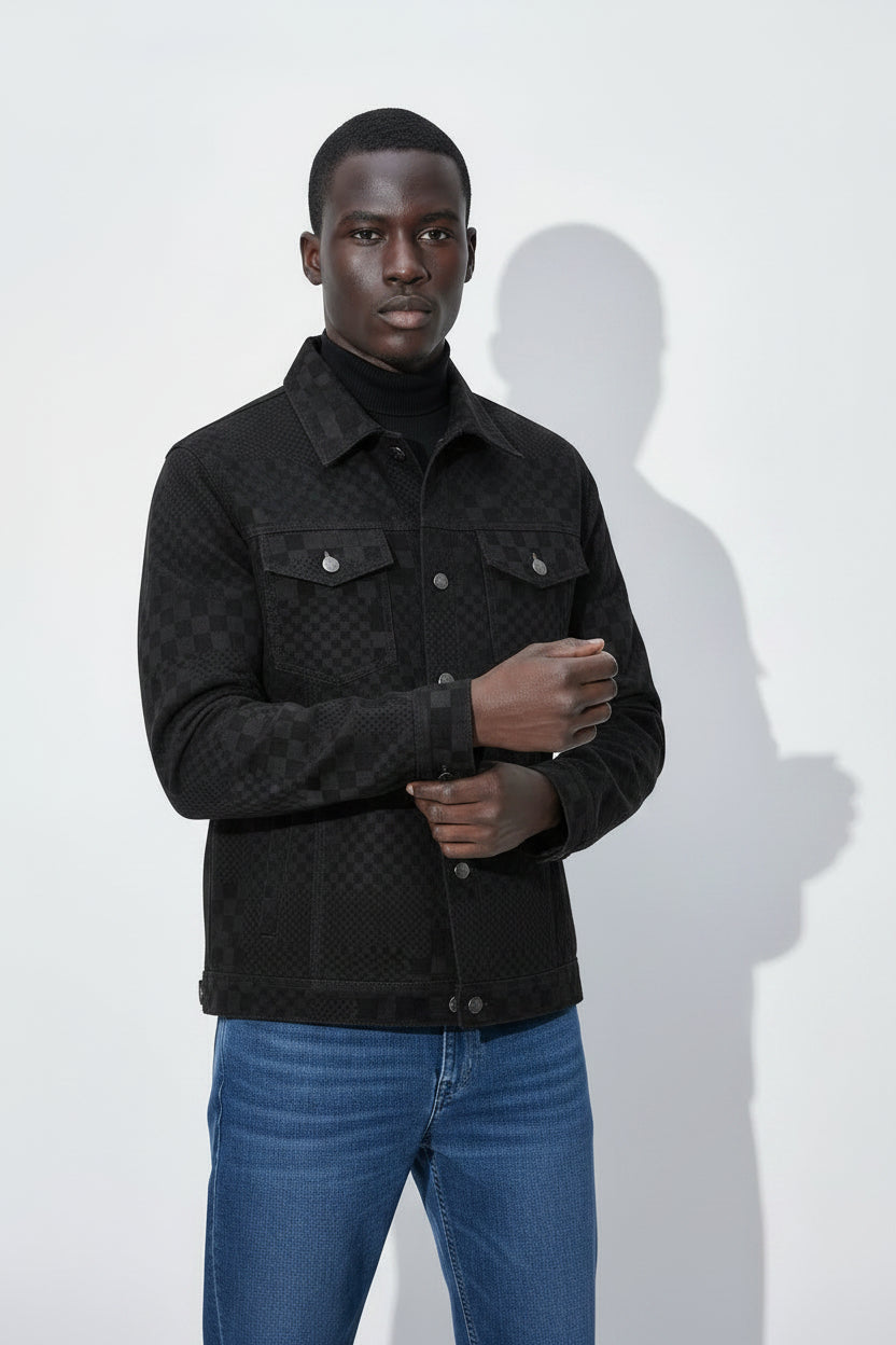 Man wearing a black quilted jacket and blue jeans against a white background