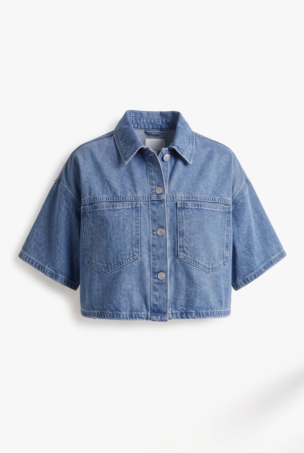 This is a medium-wash denim short-sleeved cropped jacket features a boxy, modern silhouette with relaxed drop shoulders and wide, elbow-length sleeves with stitched turned hems.