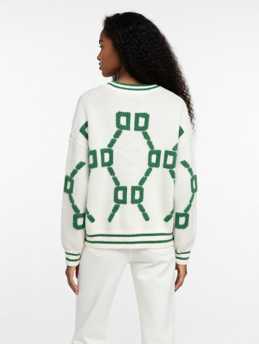 Person wearing a white sweater with green geometric patterns on a white background