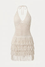 An off-white crochet halter mini dress with a tiered fringe hem, shown against a plain white background.