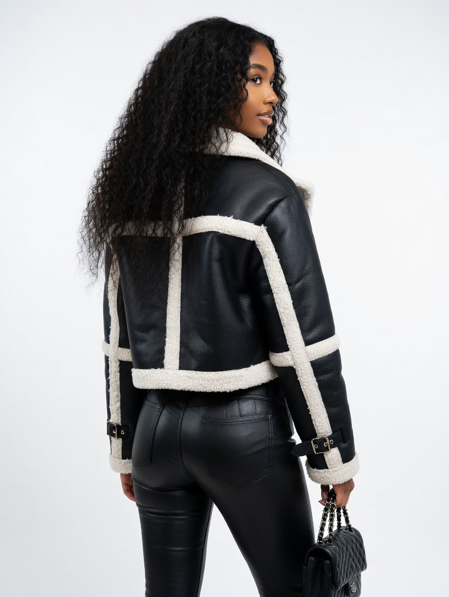 Woman wearing a black leather jacket with white shearling trim on a white background