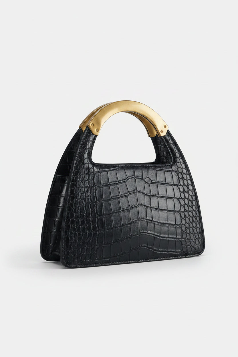 Black crocodile-patterned handbag with a brown handle on a light gray background