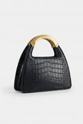 Black crocodile-patterned handbag with a brown handle on a light gray background
