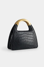 Black crocodile-patterned handbag with a brown handle on a light gray background